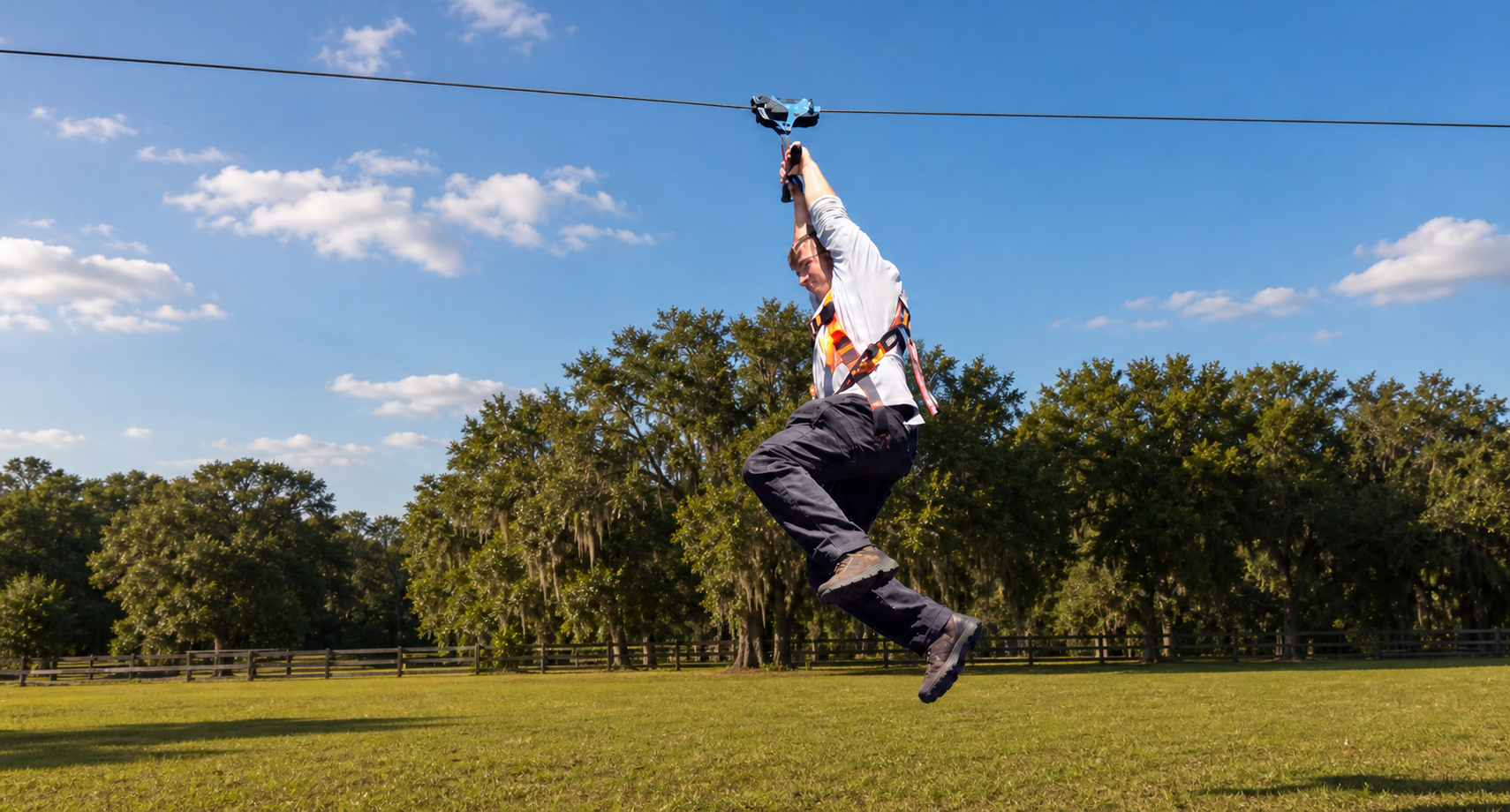 Adult rider enjoying the Zip Line over a grassy field at Raprager Farms